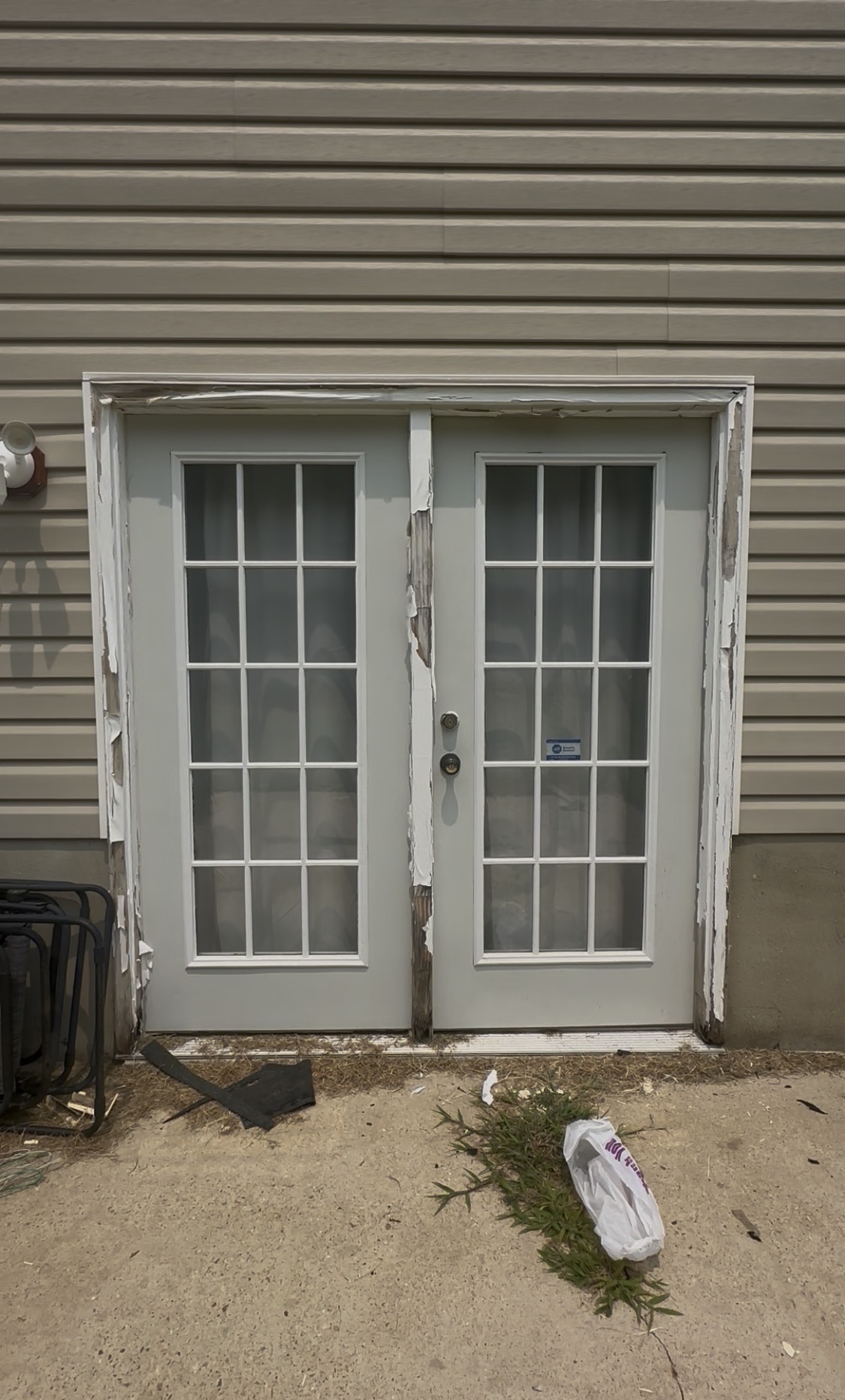 Basement French doors before repair, showing rotted and peeling wood trim exposed to weather