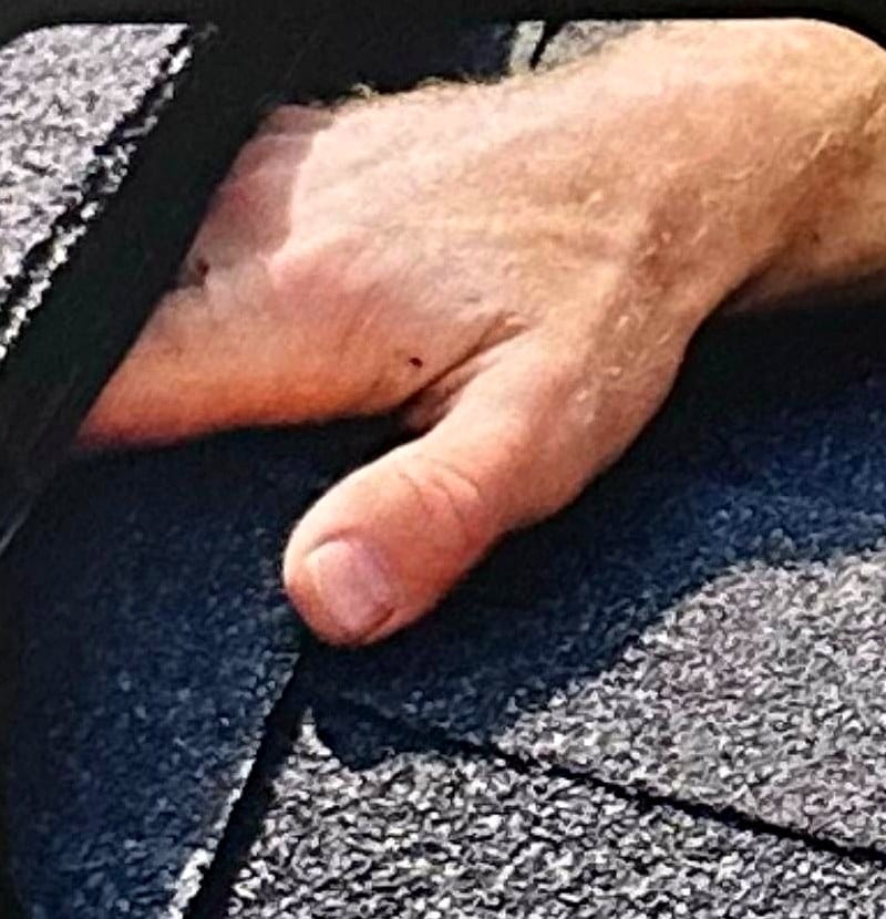 Hand lifting a shingle to show a hidden gap