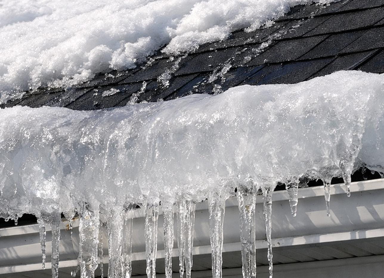 Heavy ice buildup over shingles and gutters after a winter storm