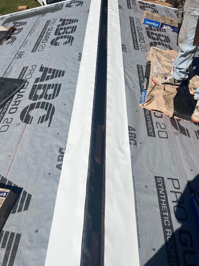Attic Armor pest barrier fastened along the roof ridge over synthetic underlayment before shingles are installed