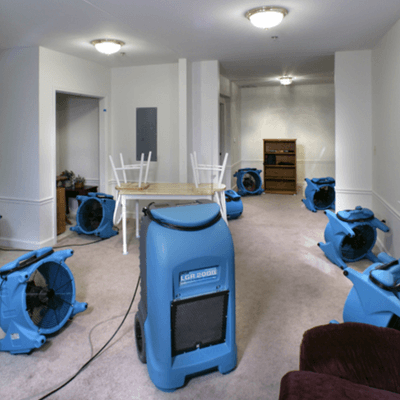 Water mitigation drying equipment: air movers and a commercial dehumidifier drying a home